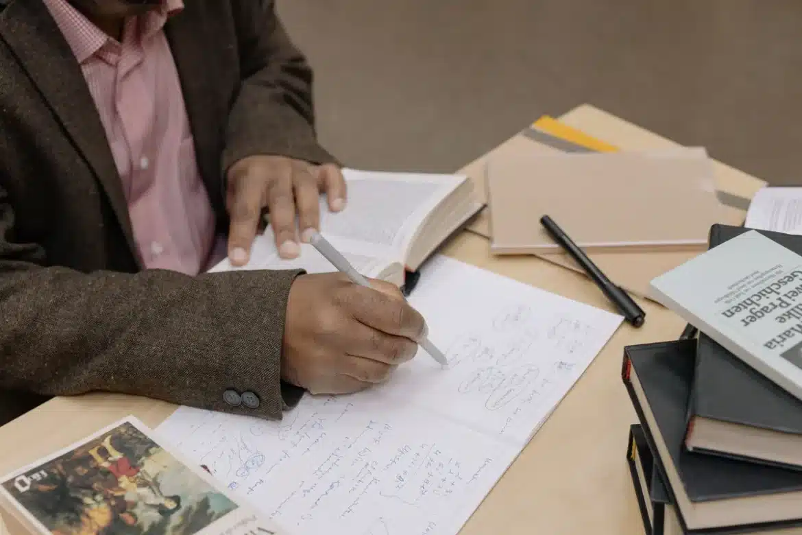 Livre ouvert sur un bureau avec notes de recherche et documents historiques en arrière-plan