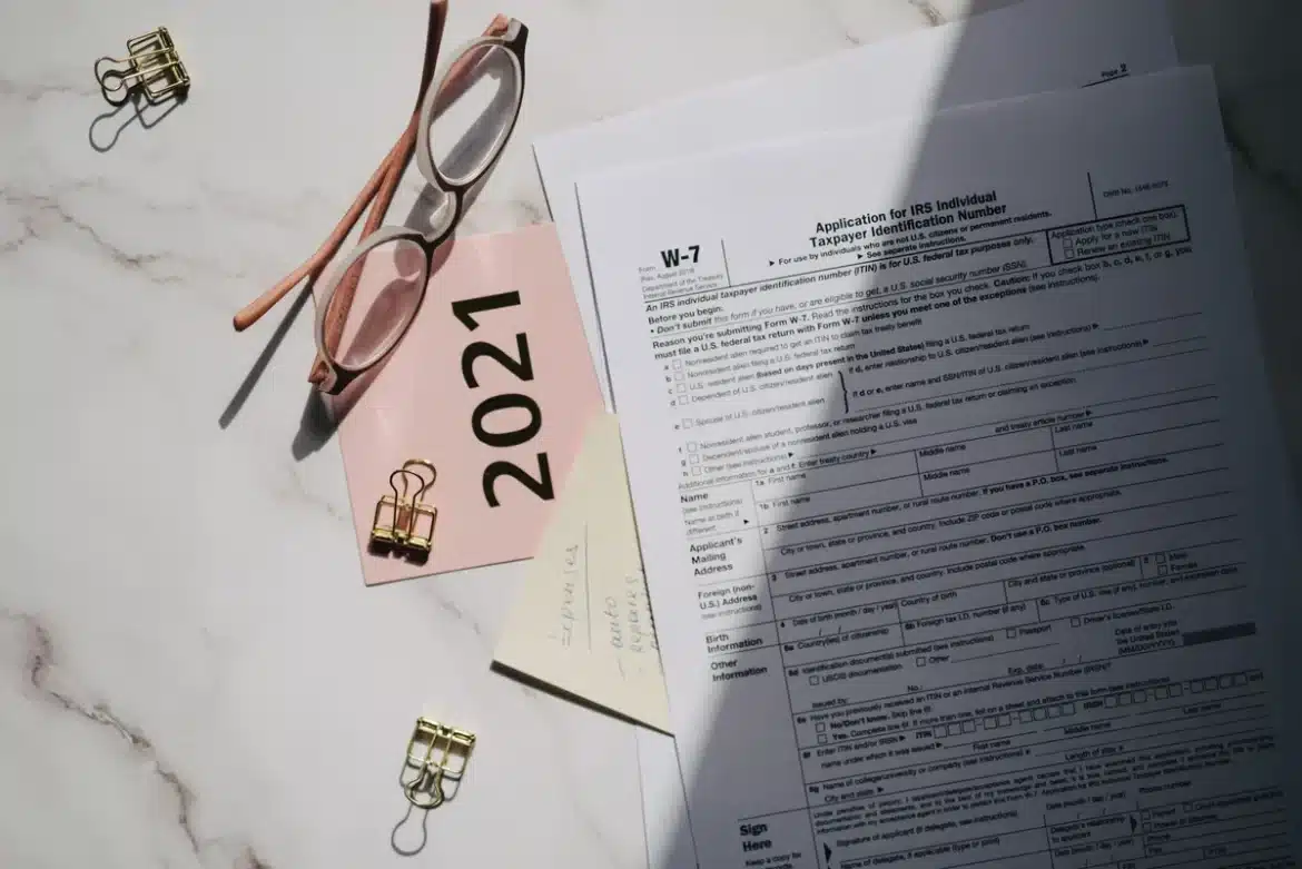 Mains tenant un chèque de don et des formulaires fiscaux sur un bureau avec calculatrice
