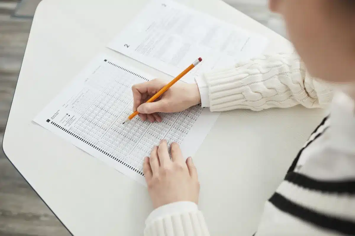 Candidat en train de passer un examen écrit, concentré sur sa copie