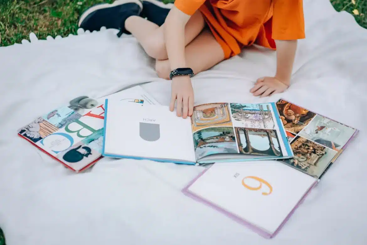 Bureau avec plusieurs livres ouverts, cartes alphabétiques et cahier de planification pour un défi de lecture A à Z.