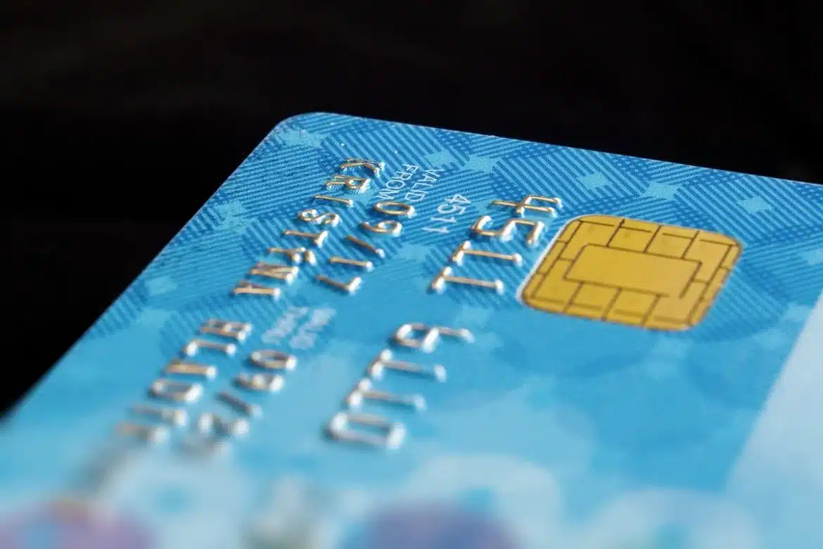 Mains tenant une carte de crédit au-dessus d'un bureau avec documents financiers et calculatrice