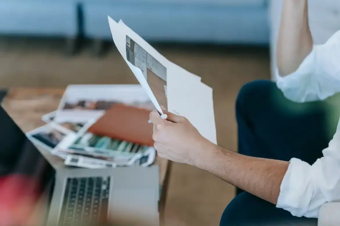 Personne travaillant sur un ordinateur portable à domicile avec des documents médicaux sur le bureau
