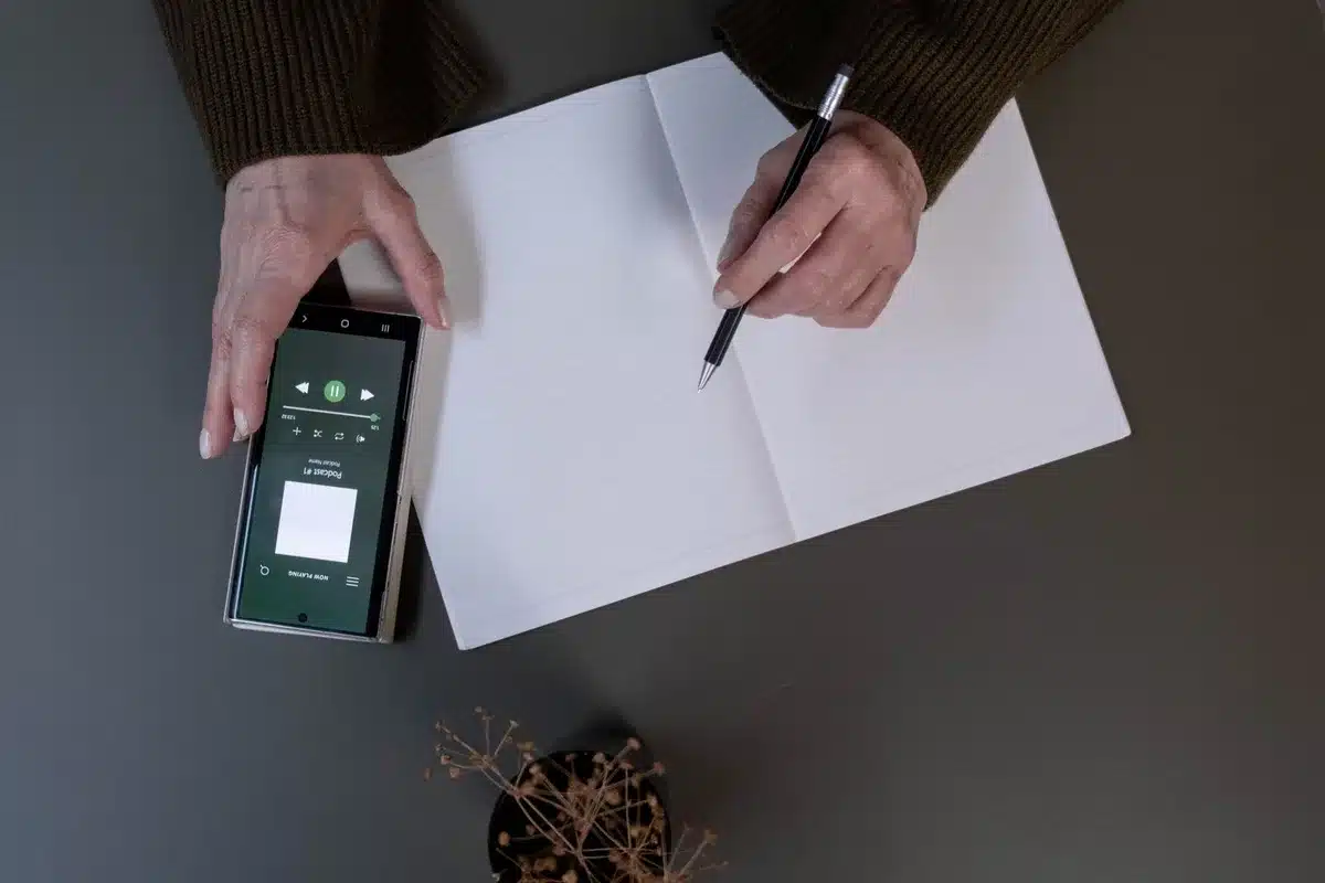 Personne prenant des notes pendant l'écoute d'un audiobook