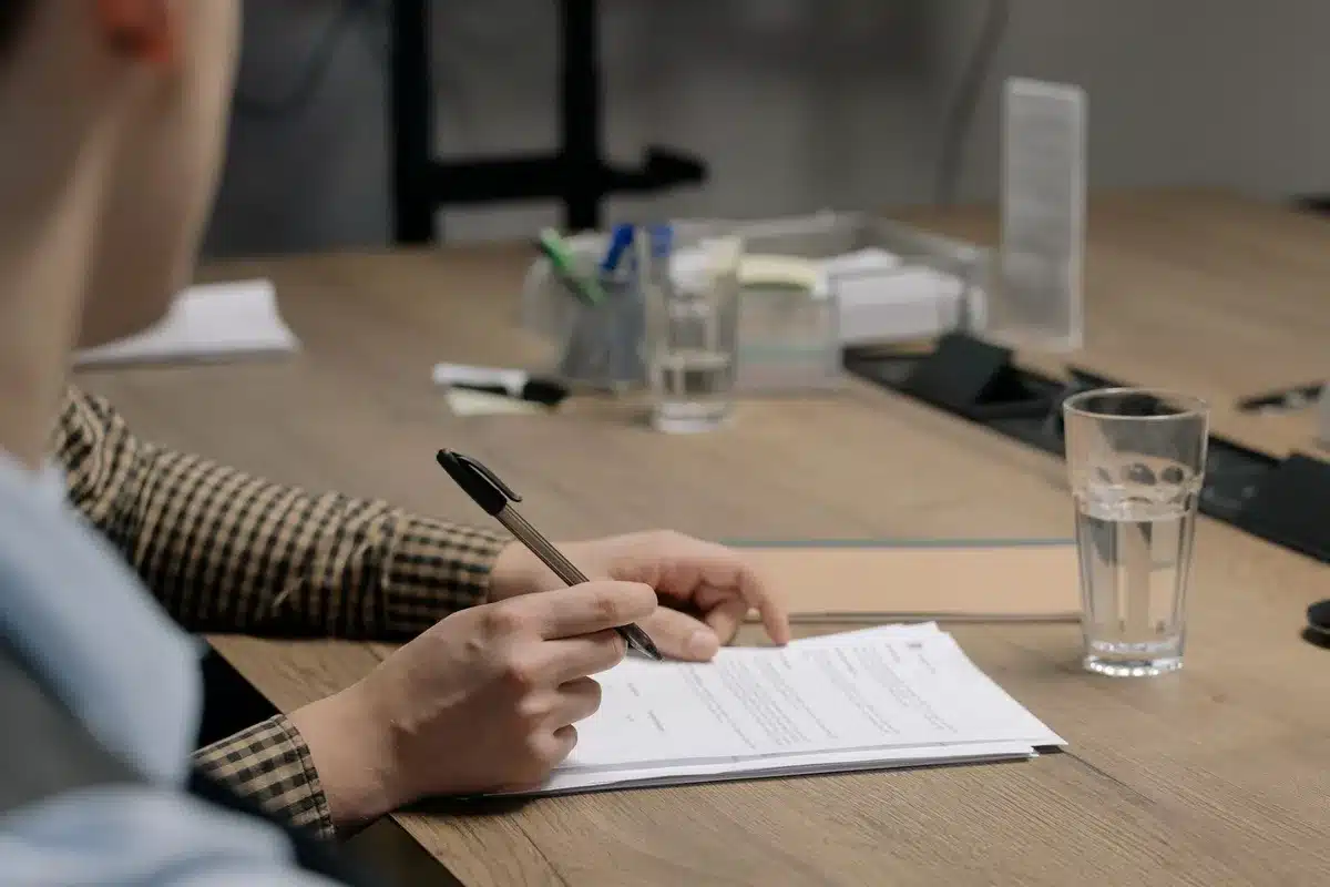 Documents professionnels, contrat de travail et fiches de paie rassemblés sur un bureau pour préparer une rupture conven
