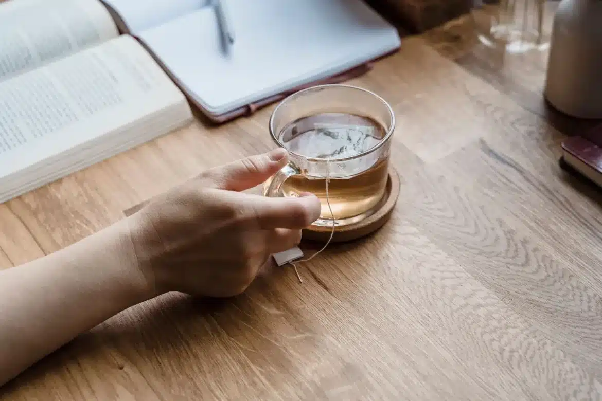 Un livre ouvert sur un bureau avec une tasse de café et un carnet de notes à proximité