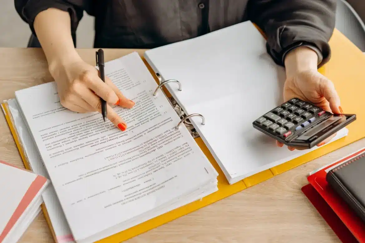 Documents hypothécaires, calculatrice et relevés financiers sur un bureau pour calculer le ratio d'endettement