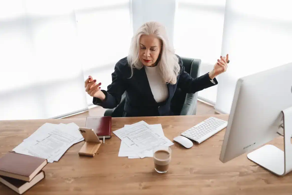 Professionnel senior travaillant à son bureau avec documents et ordinateur portable