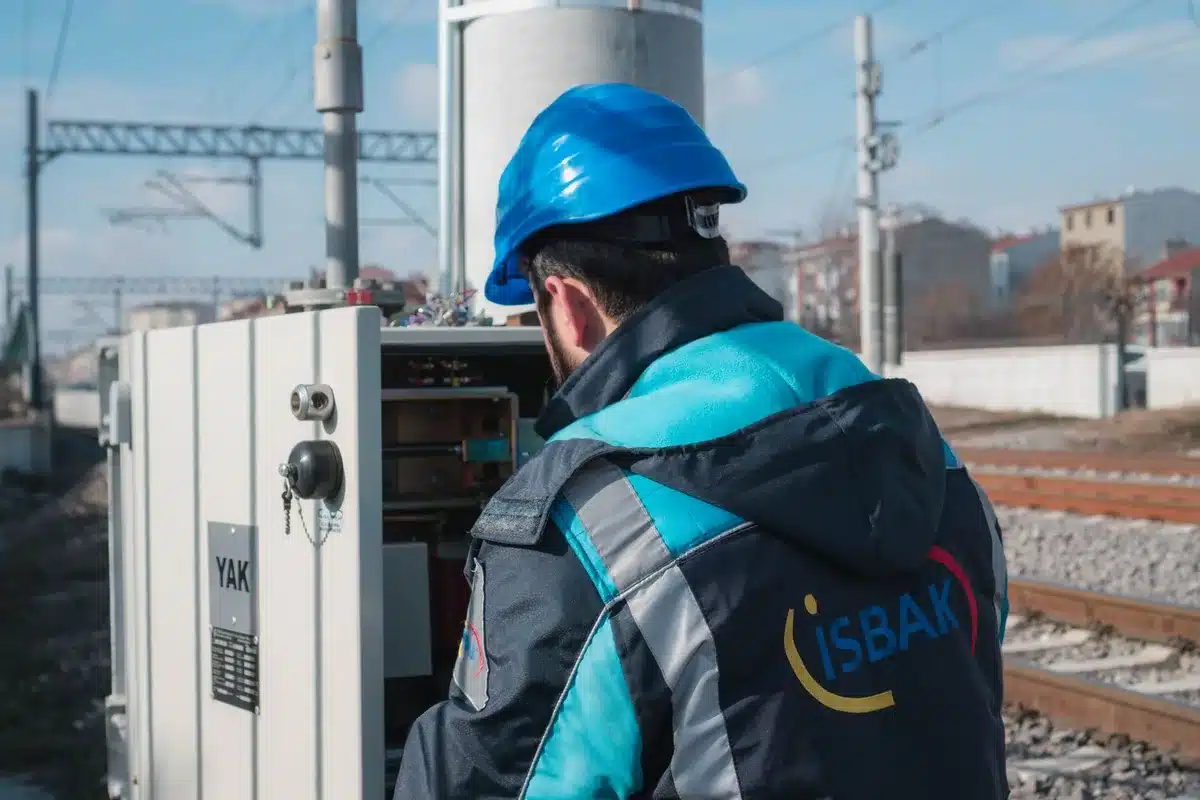 Technicien de maintenance travaillant sur l'infrastructure ferroviaire avec équipement spécialisé.