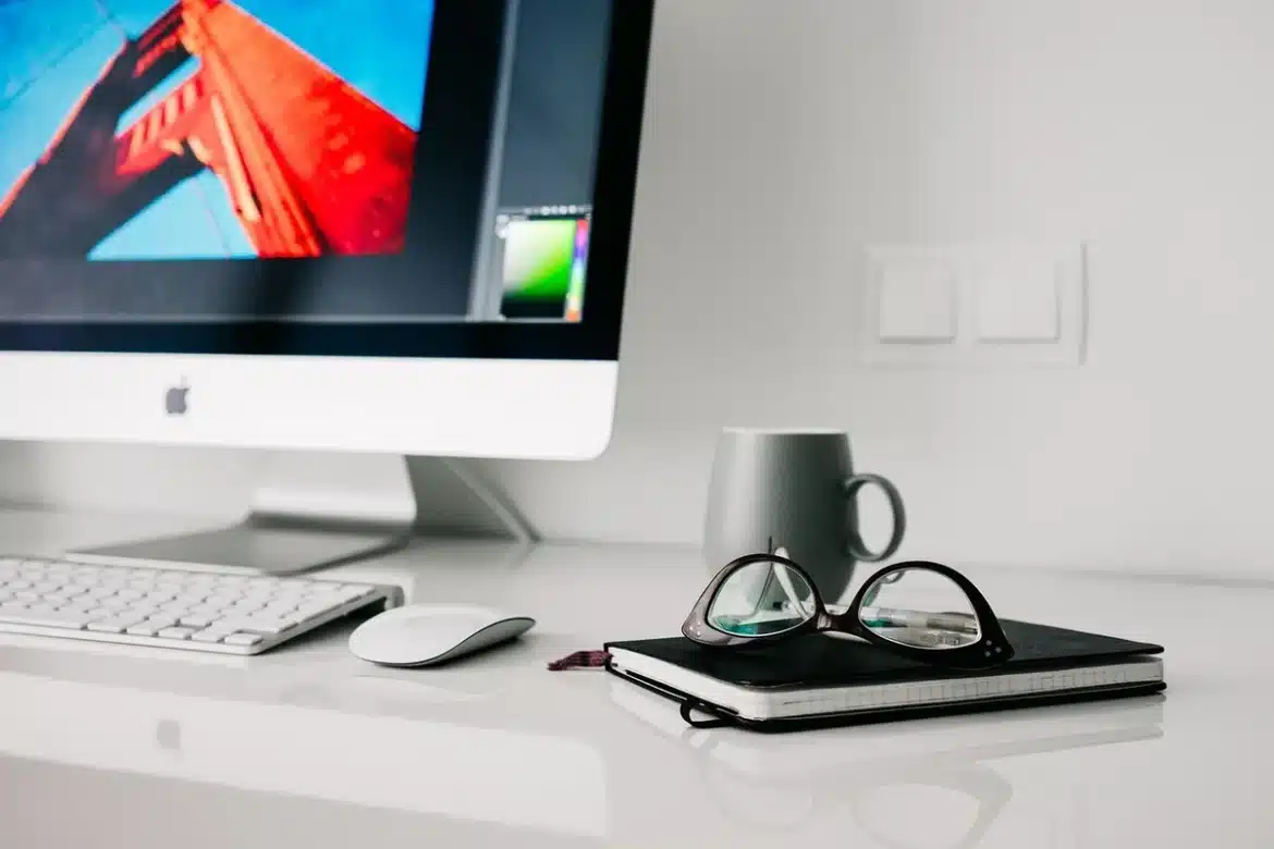 Personne au bureau à domicile, main sur le clavier, écran de l'ordinateur visible, posture détendue.