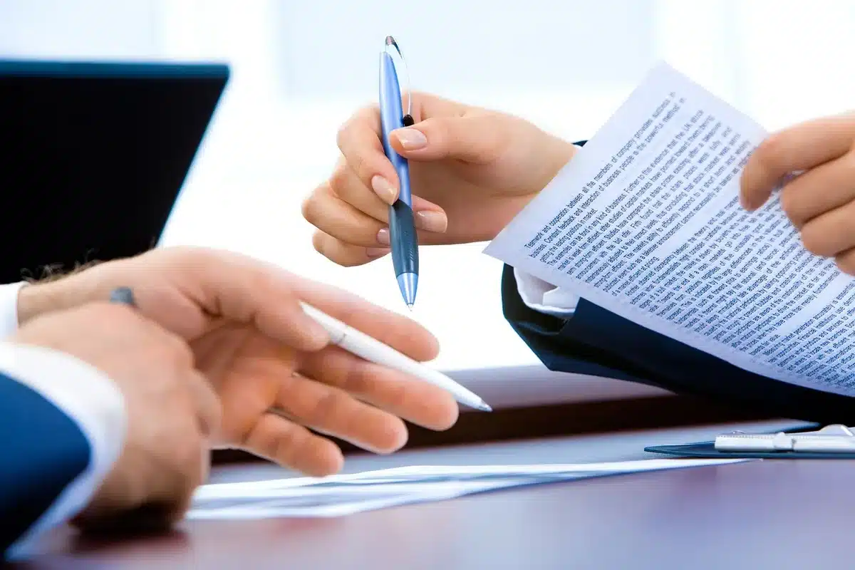 Réunion d'équipe autour d'une table avec documents et discussions constructives.