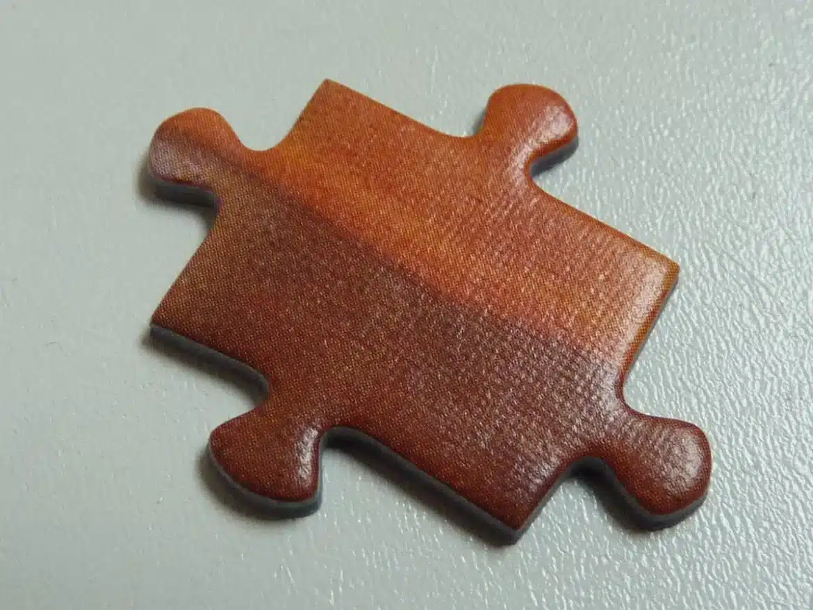 Mains assemblant des pièces de puzzle colorées sur une table en bois avec éclairage chaud