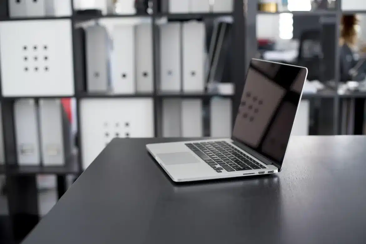 Bureau lumineux avec ordinateur portable et CV imprimé, portfolio posé près d'une fenêtre