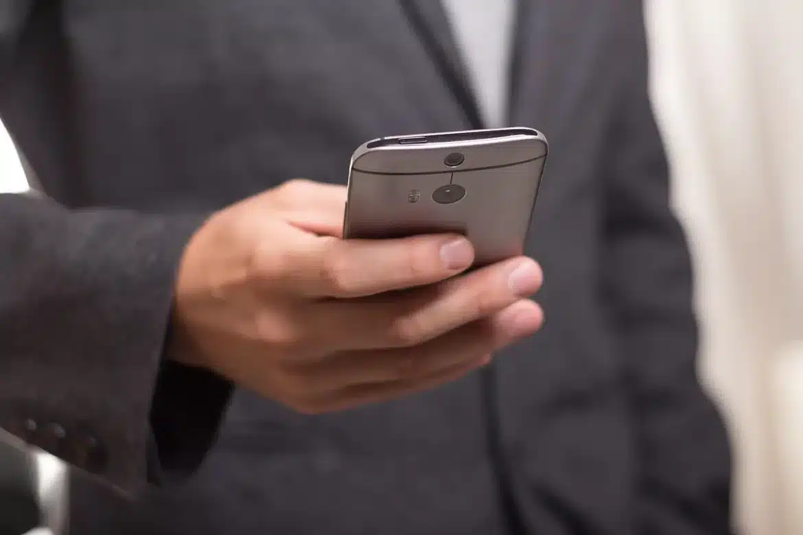 Smartphone posé sur une table de réunion avec une courte charte d'équipe, lumière du jour