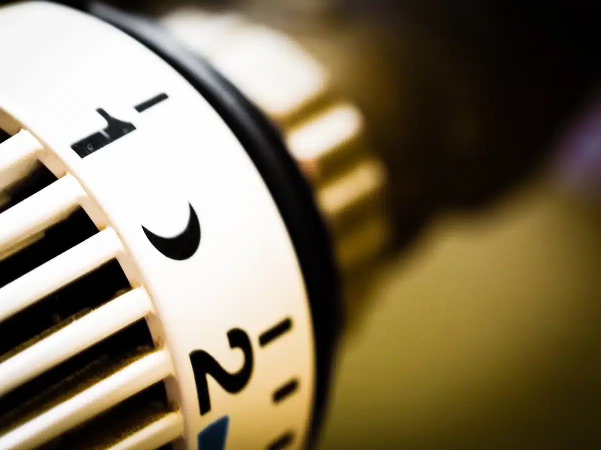 Personne examinant des factures de chauffage près d'un radiateur