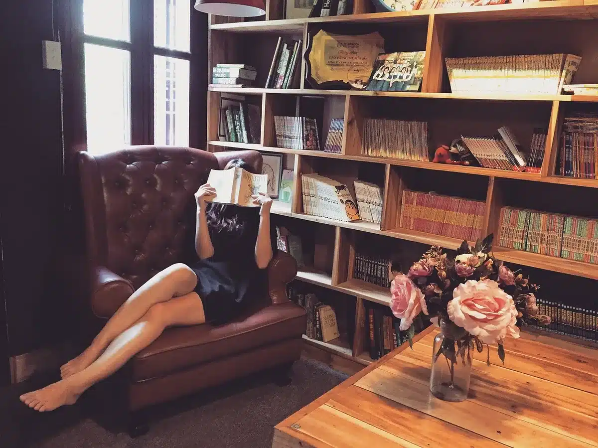 Une lectrice confortablement installée dans un fauteuil avec un livre, symbolisant l'exploration progressive du genre