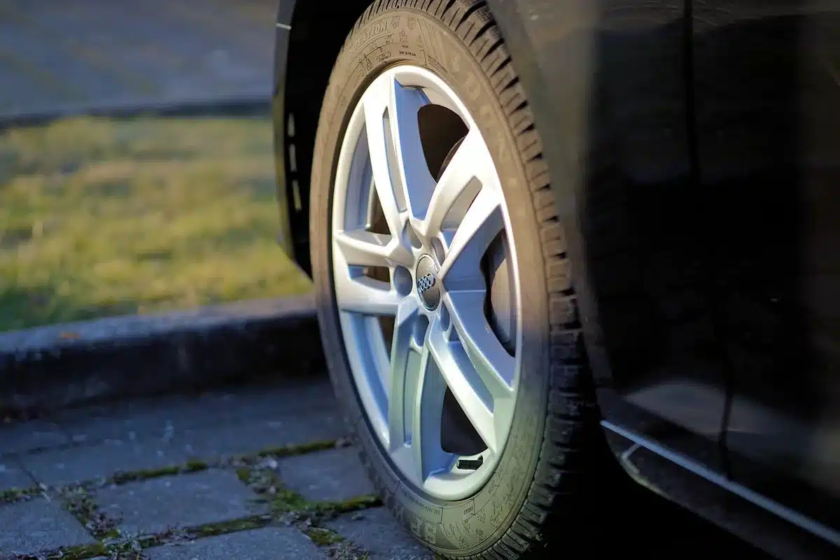 Personne vérifiant la pression d'un pneu avec un manomètre près de l'encadrement de porte