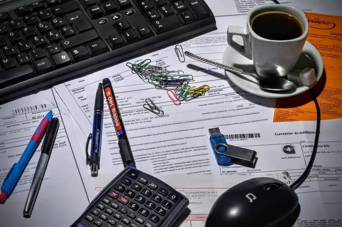 Bureau éclairé en journée avec feuille d'allocation, calculatrice et mains qui trient des fiches