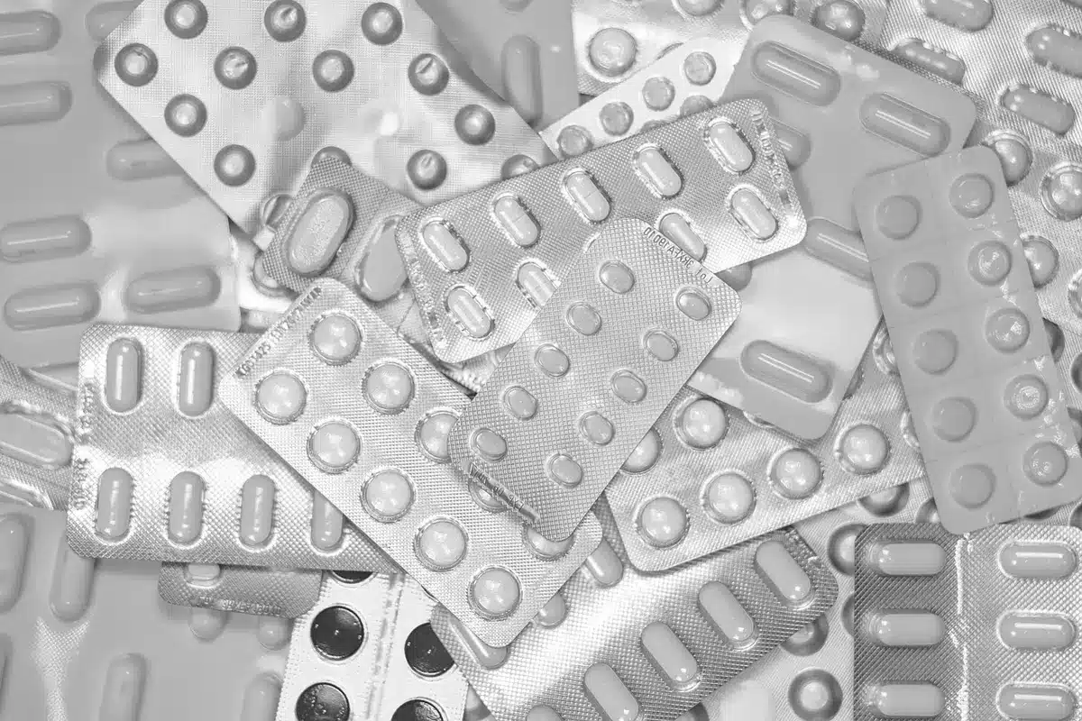 Liste de prescriptions et mains d'une personne âgée vérifiant ses médicaments