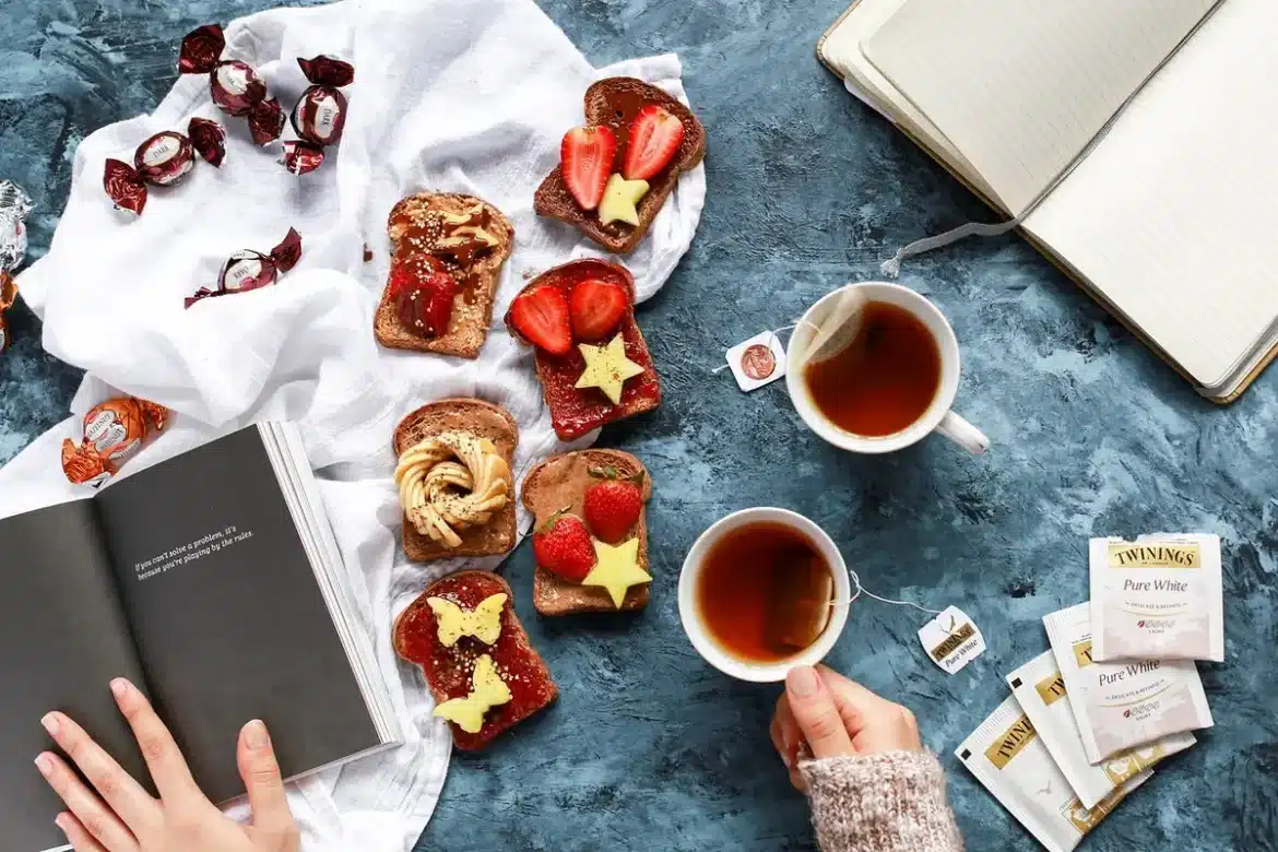 Personne anonyme feuilletant un livre sur une table ensoleillée avec lunettes et carnet